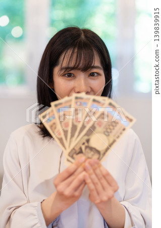 女人手中攤開五張面值10000日圓的鈔票。 139839915