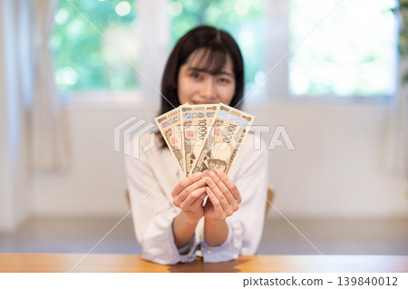 這位女士手裡拿著三張面值10,000日圓的鈔票。 139840012
