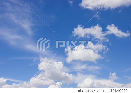 A beautiful blue sky filled with soft clouds captures the calm and beauty of a sunny day. 139840911
