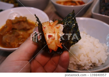 Hand Holding Korean Kimchi Rice Wrap with Side Dishes Hand Holding Korean Kimchi Rice Wrap with Side Dishes 139840957