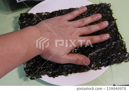 Hand Pressing Nori Seaweed on Plate Hand Pressing Nori Seaweed on Plate 139840978