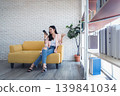 Young woman smartphone frustration sofa, casual outfit indoors home office, modern living room bookshelf background plant 139841034