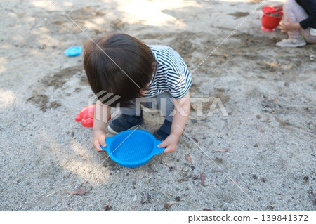 一個孩子在公園裡玩一個藍色的舊玩具。 一個孩子在公園裡玩一個藍色的舊玩具。 139841372