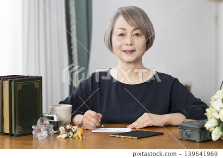 一位老婦人在客廳畫明信片。 一位老婦人在客廳畫明信片。 139841969