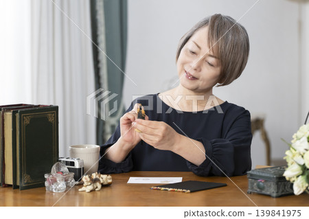 一位老婦人在客廳畫明信片。 一位老婦人在客廳畫明信片。 139841975