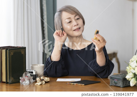 一位老婦人在客廳畫明信片。 一位老婦人在客廳畫明信片。 139841977