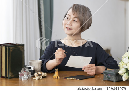 一位老婦人在客廳畫明信片。 一位老婦人在客廳畫明信片。 139841979