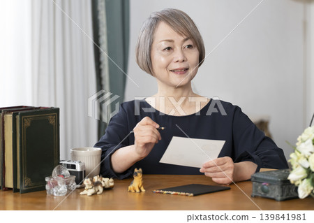一位老婦人在客廳畫明信片。 一位老婦人在客廳畫明信片。 139841981