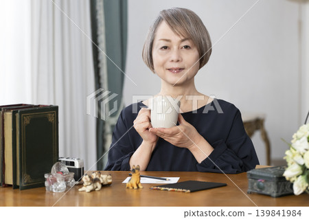 一位老婦人在客廳畫明信片。 一位老婦人在客廳畫明信片。 139841984
