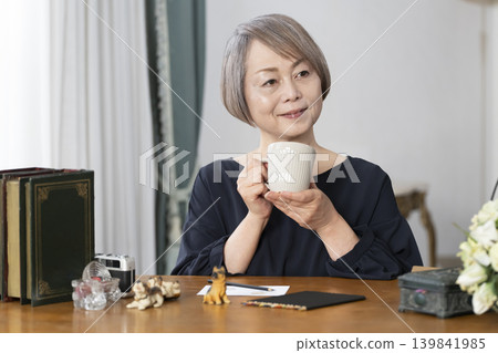 A senior woman paints picture postcards in her living room. A senior woman paints picture postcards in her living room. 139841985