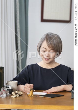 一位老婦人在客廳畫明信片。 一位老婦人在客廳畫明信片。 139841986