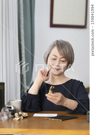 一位老婦人在客廳畫明信片。 一位老婦人在客廳畫明信片。 139841994