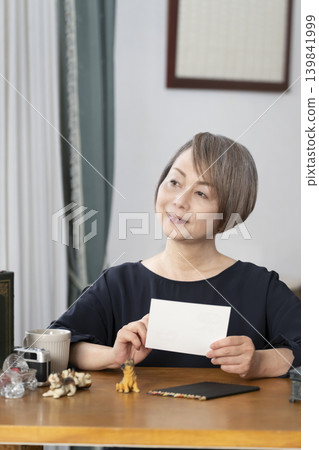 一位老婦人在客廳畫明信片。 一位老婦人在客廳畫明信片。 139841999