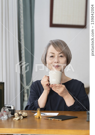 一位老婦人在客廳畫明信片。 一位老婦人在客廳畫明信片。 139842004