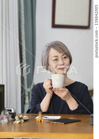 A senior woman paints picture postcards in her living room. A senior woman paints picture postcards in her living room. 139842005