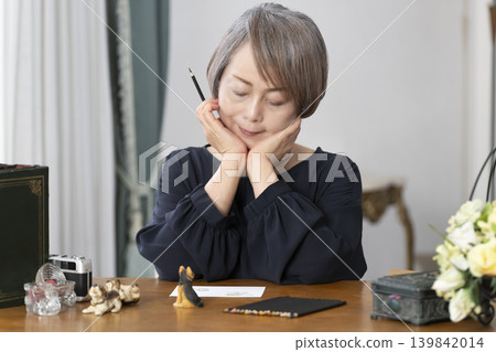 一位老婦人在客廳畫明信片。 一位老婦人在客廳畫明信片。 139842014