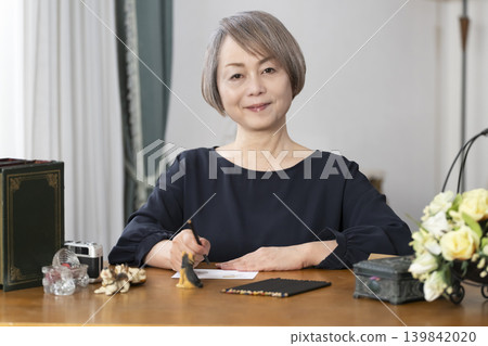 一位老婦人在客廳畫明信片。 139842020