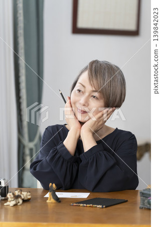 一位老婦人在客廳畫明信片。 一位老婦人在客廳畫明信片。 139842023