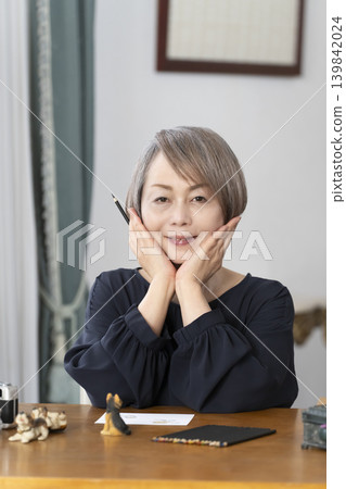 一位老婦人在客廳畫明信片。 一位老婦人在客廳畫明信片。 139842024