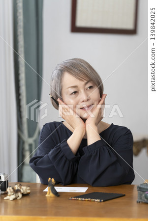 一位老婦人在客廳畫明信片。 一位老婦人在客廳畫明信片。 139842025