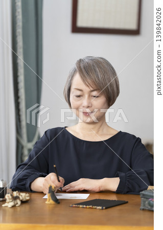 一位老婦人在客廳畫明信片。 一位老婦人在客廳畫明信片。 139842026