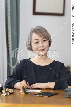 一位老婦人在客廳畫明信片。 一位老婦人在客廳畫明信片。 139842029