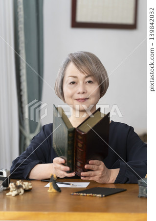 一位老婦人在客廳畫明信片。 一位老婦人在客廳畫明信片。 139842032