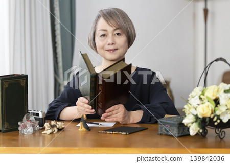 一位老婦人在客廳畫明信片。 一位老婦人在客廳畫明信片。 139842036