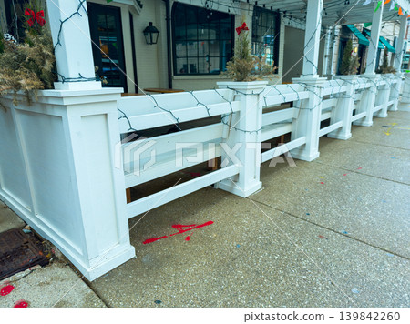 White fence surrounds outdoor seating area at cafe during winter season with holiday decorations in place for cold weather dining White fence surrounds outdoor seating area at cafe during winter season with holiday decorations in place for cold weather dining 139842260