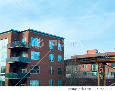 Building with windows and balcony near elevated train tracks in an urban area on a clear day Building with windows and balcony near elevated train tracks in an urban area on a clear day 139842292