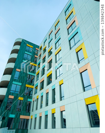 Colorful building exterior with modern design in an urban area during daytime with clear blue sky Colorful building exterior with modern design in an urban area during daytime with clear blue sky 139842348