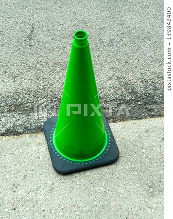 Traffic cone stands on asphalt near a road marking during a sunny day in an urban area Traffic cone stands on asphalt near a road marking during a sunny day in an urban area 139842400