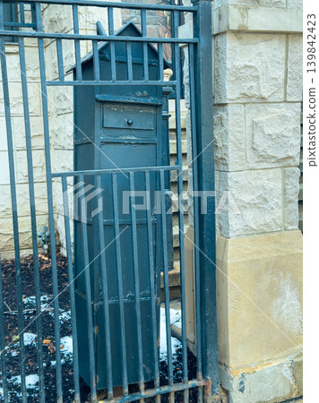 Mailbox stands outside a gated entrance near a stone building on a winter day in a quiet neighborhood Mailbox stands outside a gated entrance near a stone building on a winter day in a quiet neighborhood 139842423