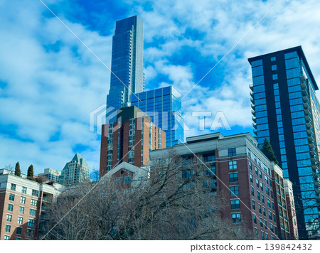 City skyline view shows modern buildings under bright blue sky with clouds in the background on a clear day in downtown area City skyline view shows modern buildings under bright blue sky with clouds in the background on a clear day in downtown area 139842432