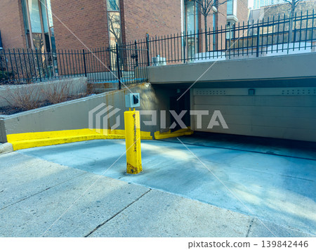 Parking area with entrance ramp leading to underground section located in a city setting during daylight hours Parking area with entrance ramp leading to underground section located in a city setting during daylight hours 139842446