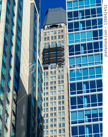 Buildings meet in the city with a clear sky above, showing different architecture styles during a sunny day Buildings meet in the city with a clear sky above, showing different architecture styles during a sunny day 139842452