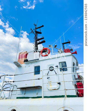 View of the upper deck of a boat showing equipment, safety features, and sky in the background during sunny weather at the harbor View of the upper deck of a boat showing equipment, safety features, and sky in the background during sunny weather at the harbor 139842503