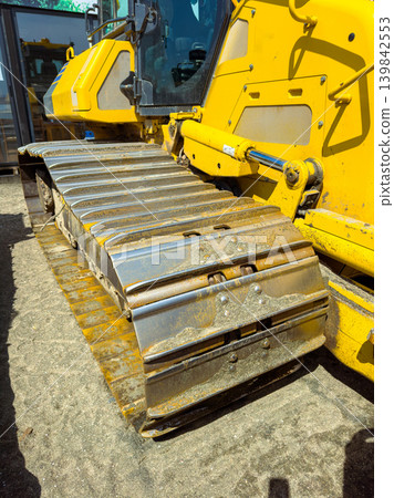 Heavy equipment tracks on a bulldozer at a construction site in the afternoon sun 139842553