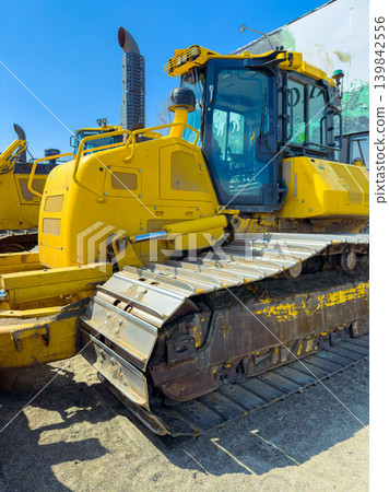 Excavator parked at construction site with blue sky in background during daytime near industrial area Excavator parked at construction site with blue sky in background during daytime near industrial area 139842556