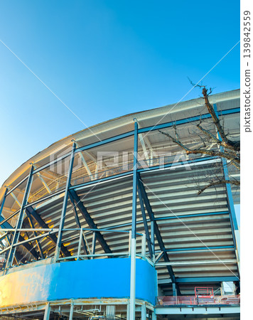 New sports stadium construction in the city with metal structure and clear sky in the background during early morning hours New sports stadium construction in the city with metal structure and clear sky in the background during early morning hours 139842559