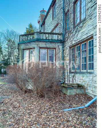 Old house in a quiet area surrounded by dry leaves and bare shrubs during daytime Old house in a quiet area surrounded by dry leaves and bare shrubs during daytime 139842561
