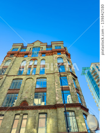 Historic building shows its tall structure against a clear sky in a city, highlighting its windows and unique architectural design during the daytime Historic building shows its tall structure against a clear sky in a city, highlighting its windows and unique architectural design during the daytime 139842580