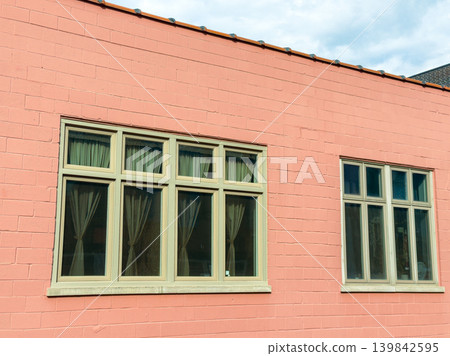 Building with pink wall and windows in urban area during daytime with clouds Building with pink wall and windows in urban area during daytime with clouds 139842595