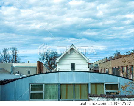 Cloudy sky over buildings with a house in the background near the urban area during the daytime in a city setting Cloudy sky over buildings with a house in the background near the urban area during the daytime in a city setting 139842597