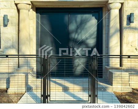 Dark door with a gate in front, sunlight shining on the building structure during the late afternoon in a city Dark door with a gate in front, sunlight shining on the building structure during the late afternoon in a city 139842602