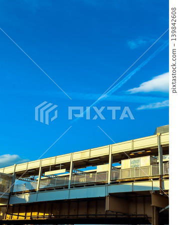 Clouds form shapes in the blue sky above an elevated walkway in an urban area during the afternoon Clouds form shapes in the blue sky above an elevated walkway in an urban area during the afternoon 139842608