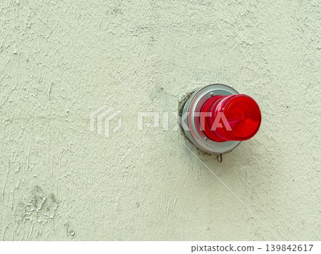 Emergency light mounted on a wall shining bright red in a commercial building during daylight hours Emergency light mounted on a wall shining bright red in a commercial building during daylight hours 139842617
