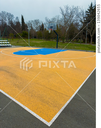 Empty basketball court with blue markings located in a park during a cloudy day with no people around Empty basketball court with blue markings located in a park during a cloudy day with no people around 139842655