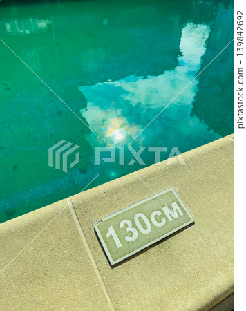 Swimming pool with a depth marker showing 130 cm during a sunny day in a residential area Swimming pool with a depth marker showing 130 cm during a sunny day in a residential area 139842692