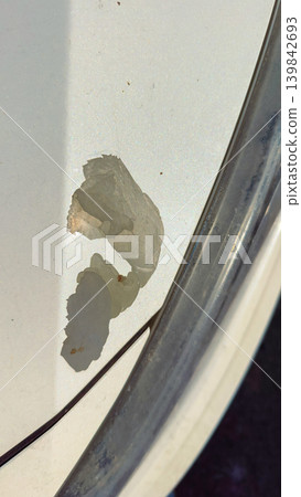 Dents and scratches appear on the white car surface during a sunny day while parked in a public area Dents and scratches appear on the white car surface during a sunny day while parked in a public area 139842693